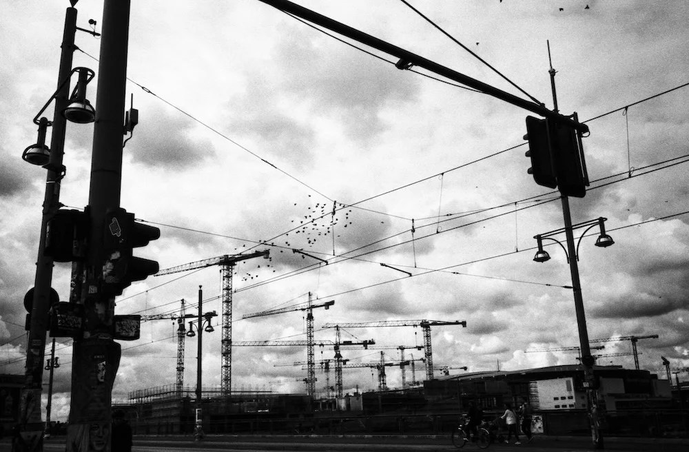 A moody black and white film image of Berlin showing the sky crossed by cables.