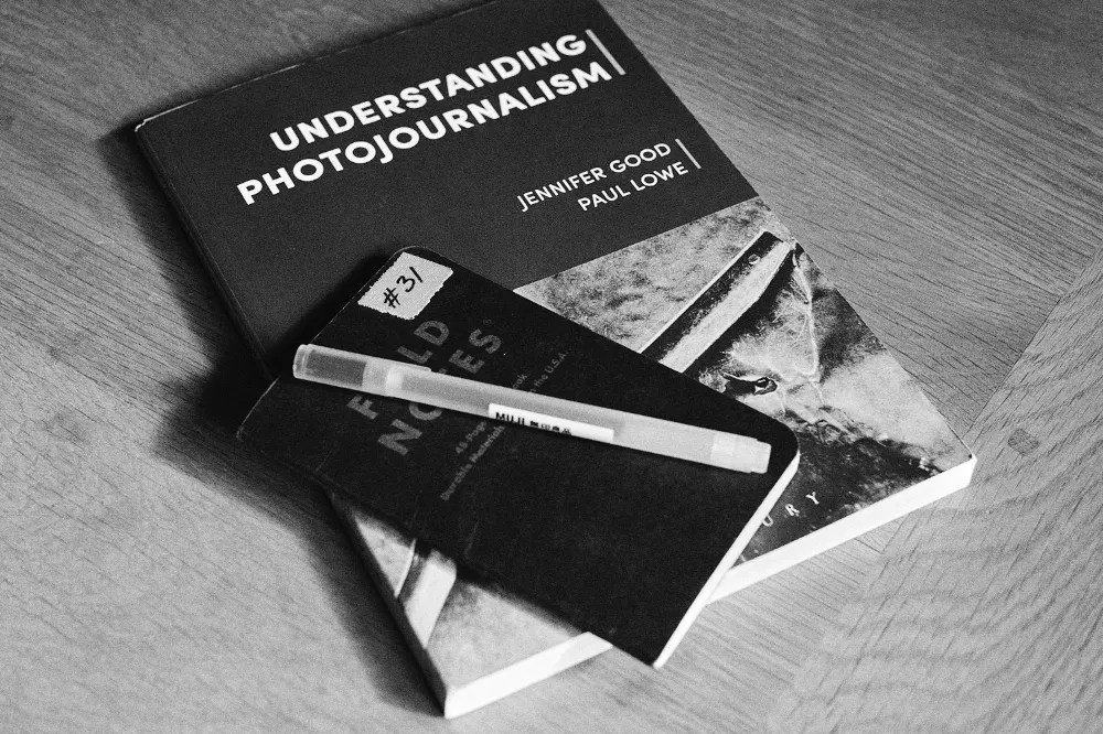 A documentary photography text book, notebook and pen.