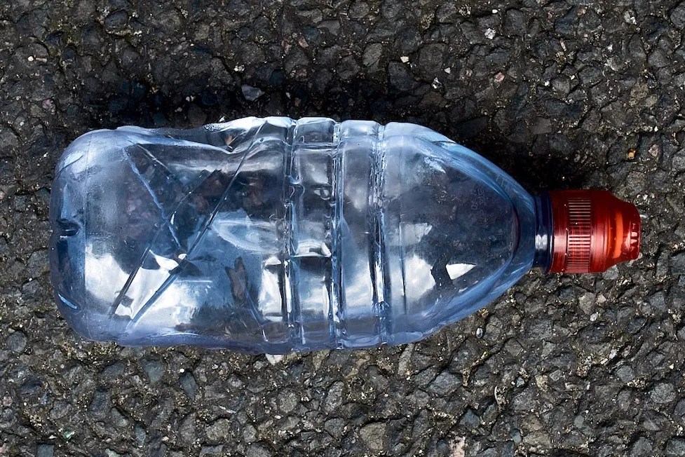 A discarded plastic water bottle with a red cap.